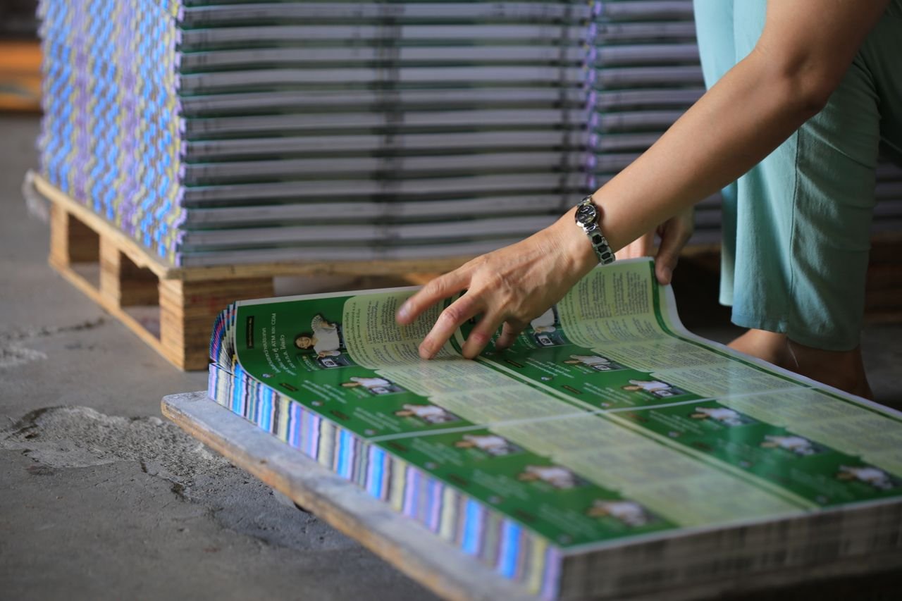 Home A person organizes stacks of printed publications in an industrial warehouse setting.