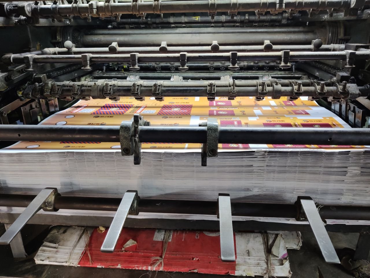 Services Close-up of an industrial printing machine processing paper sheets in a factory setting.